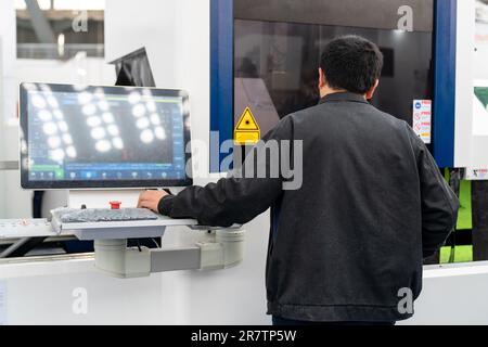 Worker controls automatic machine tool in smart factory. Stock Photo