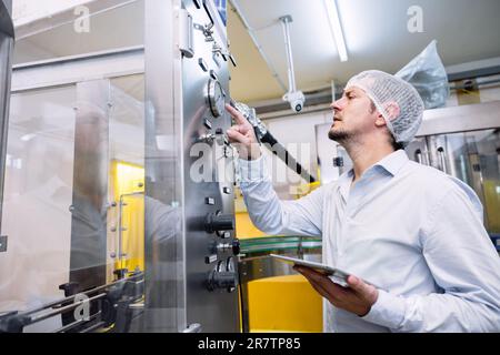 Engineer male working setup automatic machine in food beverage industry factory. Stock Photo