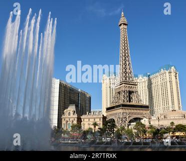 Bellagio resort fountains during a display with the fake half scale Eiffel Tower at the Paris casino and resort in afternoon sun Las Vegas Nevada USA Stock Photo