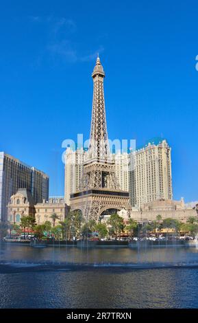 Bellagio resort fountains during a display with the fake half scale Eiffel Tower at the Paris casino and resort in afternoon sun Las Vegas Nevada USA Stock Photo