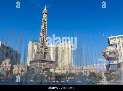 Bellagio resort fountains during a display with the fake half scale Eiffel Tower at the Paris casino and resort in afternoon sun Las Vegas Nevada USA Stock Photo