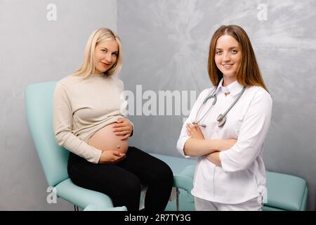 Gynecologist preparing for an examination procedure for a pregnant woman sitting on a gynecological chair in the office and smiling. Stock Photo