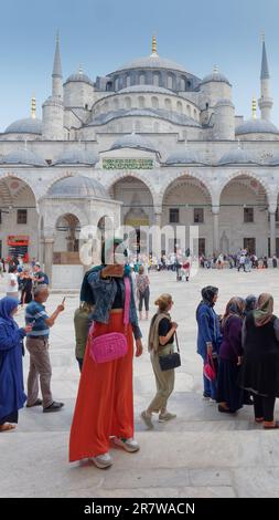 Woman wearing an orange skirt, denim jacket and hijab takes a selfie in the courtyard of the Sultan Ahmed Mosque aka Blue Mosque. Istanbul, Turkey Stock Photo