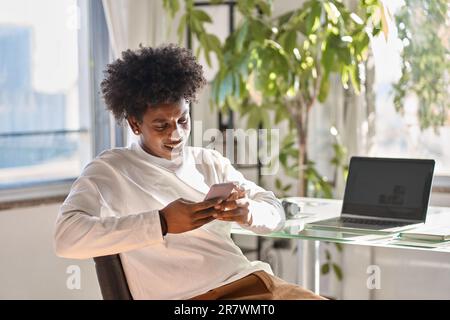 Gen z African American teenager using mobile phone at home. Stock Photo