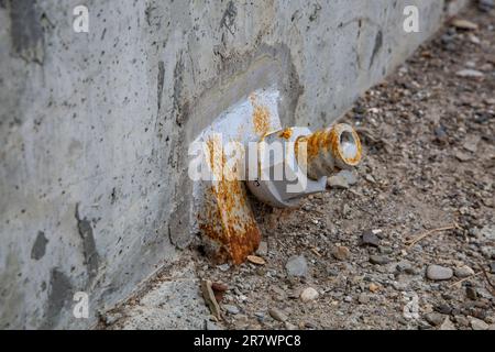 twisted metal nut covered with rust on the concrete wall of the bridge. Details of steel construction Stock Photo