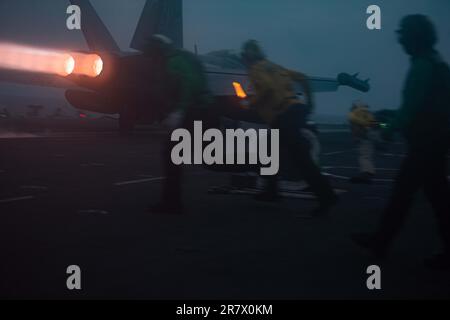 230615-N-UF592-1021 SOUTH CHINA SEA (June 15, 2023) Sailors move to their positions as an EA-18G Growler, attached to the Shadowhawks of Electronic Attack Squadron (VAQ) 141, launches from the flight deck of the U.S. Navy’s only forward-deployed aircraft carrier, USS Ronald Reagan (CVN 76), in the South China Sea, June 15, 2023. The primary role of EA-18G Growlers is to disrupt the ability to communicate between units in combat through the use of electronic warfare. Ronald Reagan, the flagship of Carrier Strike Group 5, provides a combat-ready force that protects and defends the United States, Stock Photo