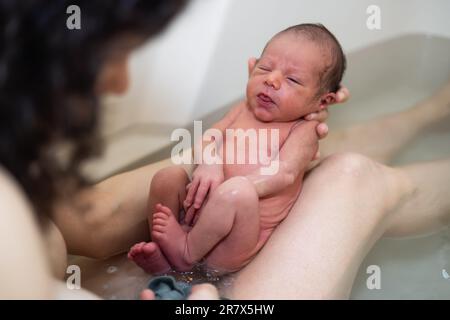 Adorable Newborn Baby Boy taking a bath with mother Stock Photo