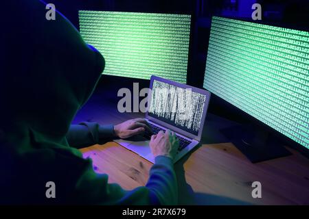 Hacker working with computers at wooden table indoors. Cyber attack Stock Photo