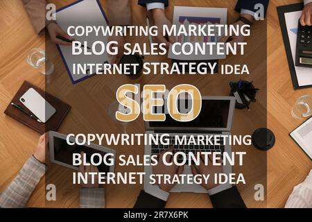 Search engine optimization (SEO). Many terms above marketing team developing strategy of internet promotion at wooden table, top view Stock Photo