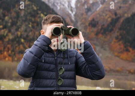 Boy looking through binoculars in beautiful mountains Stock Photo