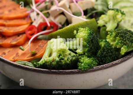 Bowl with many different vegetables on grey table, closeup. Vegan diet Stock Photo