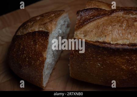 Homemade sourdough crusty loaves of bread on wooden background.  Still life concept. Dark moody. Stock Photo