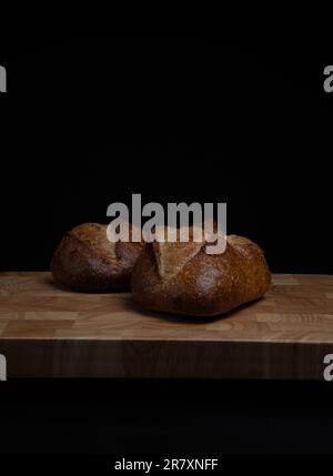 Homemade sourdough crusty loaves of bread on wooden background.  Still life concept. Dark moody. Stock Photo