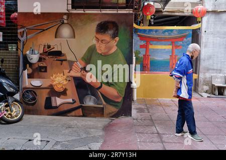Murals in a lane in Chinatown, Bangkok, Thailand, depicting a craftsman at work and a Chinese-style arch, red Chinese-style lanterns hanging overhead Stock Photo