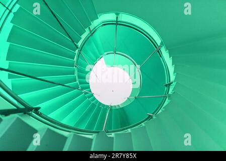 Upward view in a high building with helical staircase. The room, turquoise colored, is situated in a hotel foyer Stock Photo