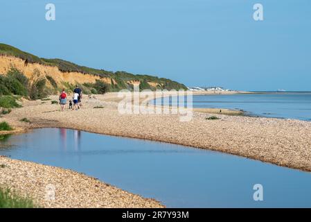 Quiet English beach scene, with families walking dogs and sitting down to catch the sun. This is Titchfield Haven in Hampshire, May 2023. Stock Photo