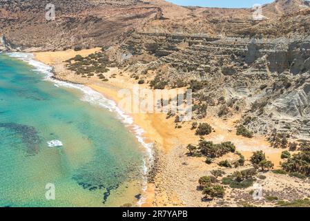 Potamos bay with the long reddish beach and shallow water, formed at the exit of a small canyon with majestic geological clay formations and steep Stock Photo