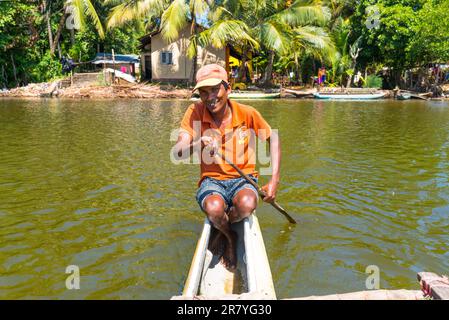 Sri Lankan canoeist, fisherman and guide with an outrigger canoe, shows tourists the attractions of the Hikkaduwa lake Stock Photo