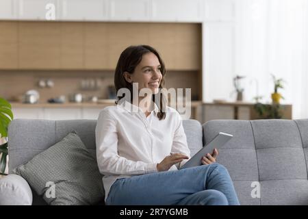 Pretty female relaxing on couch with modern digital tablet Stock Photo