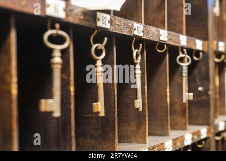 A collection of old keys hanging on wooden shelves in a room Stock Photo