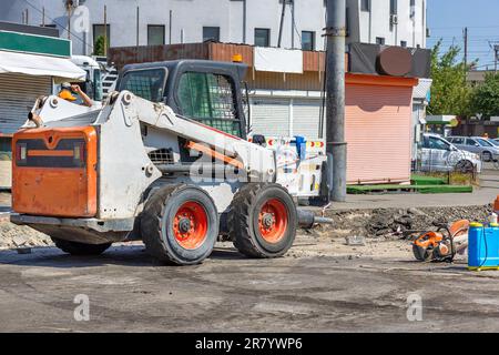 On the repaired section of the carriageway, compact and powerful construction equipment is parked along with a petrole cutter. Copy space. Stock Photo