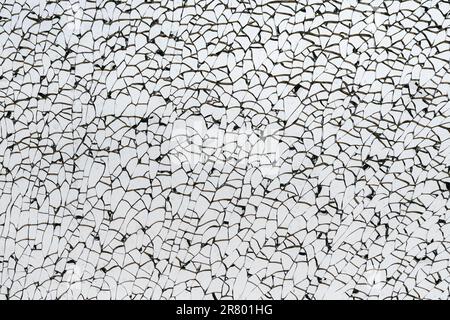 Macro closeup of a broken glass window. Cracks run throughout the glass, but no hole visible. Stock Photo