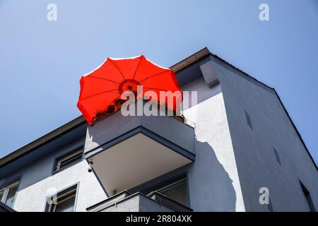 red parasol on a balcony of a grey residential house on Ursulagarten street, Cologne, Germany. roter Sonnenschirm auf einem Balkon eines grauen Wohnha Stock Photo