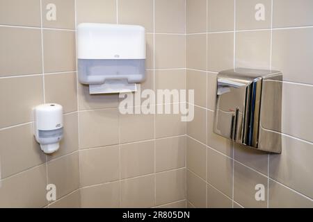 Soap dispenser Tork, holder for paper towels and hand dryer device Algostar on the wall in the bathroom - Moscow, Russia, March 30, 2019 Stock Photo