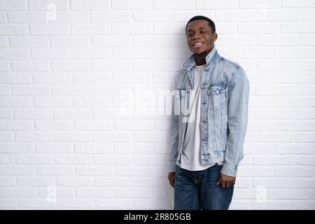 Portrait young handsome african black man wearing denim jeans jacket against brick with wall outdoors with copyspace. Stock Photo