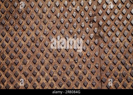 Rusty worn out tread plate with a diamond pattern used for slip resistance. Old metal sheet with a rhombus pattern, industrial background Stock Photo