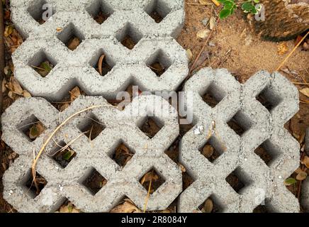 Turfstone pavers with holes for grass at a construction site, ready for installment. Lattice-grid concrete paving blocks lying on the ground Stock Photo