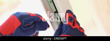 Hands of master with screwdriver repairing adjustment or installation of metal-plastic windows in apartment Stock Photo