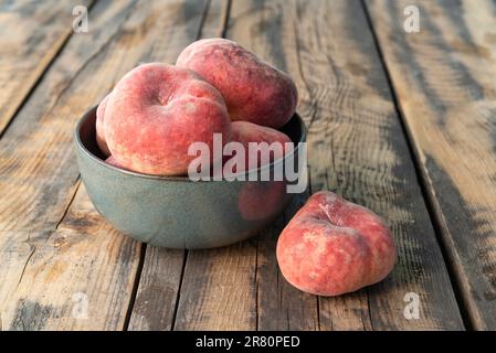 Ceramic bowl with donut peaches on a wooden table Stock Photo