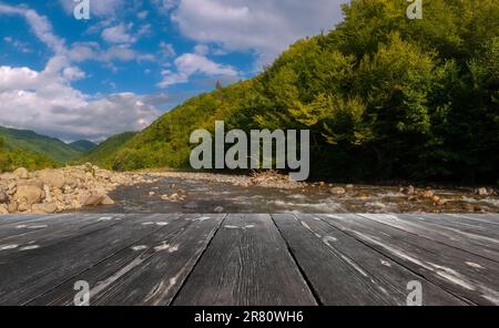 Fast mountain river flowing with empty wooden batten bridge. Natural ...
