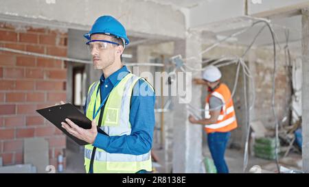 Two men builders writing document working at construction site Stock Photo