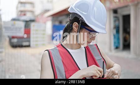 Young beautiful hispanic woman builder standing with serious expression looking down at street Stock Photo