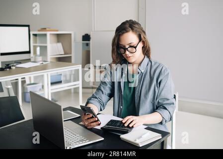 Professional Woman Accountant Managing Finances: Using Calculator and Computer in Office. Finance and Accounting Concept for Business, Financial Stock Photo