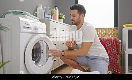 Young hispanic man doing laundry at laundry room Stock Photo