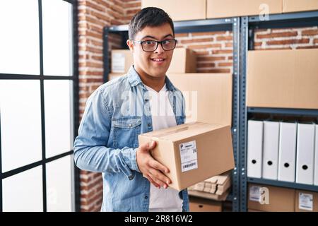 Down syndrome man ecommerce business worker holding package at office Stock Photo
