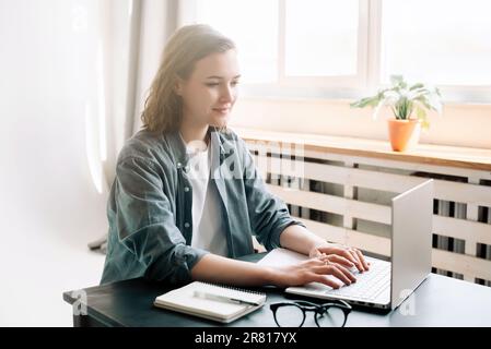 Young woman using laptop computer in a modern office setting and student girl working from the comfort of home. Online work, study, freelance Stock Photo