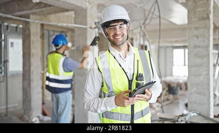 Two men builders smiling confident using touchpad at construction site Stock Photo