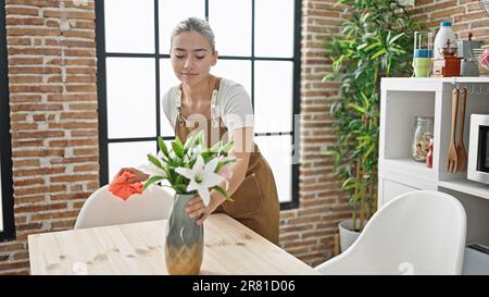 Young beautiful hispanic woman wearing apron cleaning table at dinning room Stock Photo