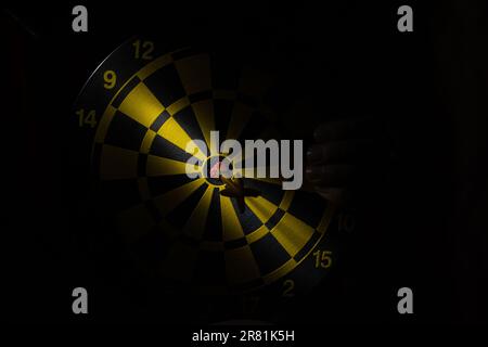 Darts and darts in the dark and a beam of light in the center close up and a woman's hand Stock Photo
