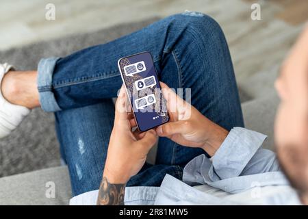 Cropped of stylish man sitting outdoors, using AI on smartphone Stock Photo