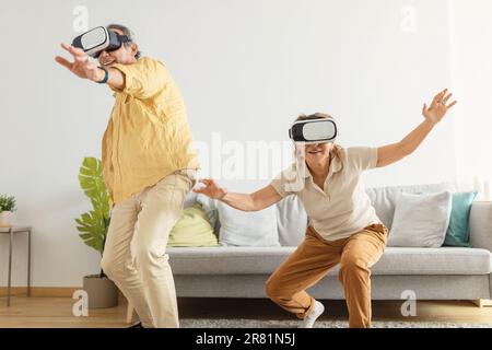 Interactive gaming concept. Senior spouses having fun in VR headsets, experiencing virtual reality adventure Stock Photo