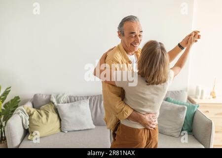 Romantic senior spouses dancing together in living room, enjoying spending time with each other at home, free space Stock Photo