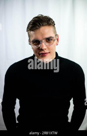 A Close up portrait of a young adult Caucasian man wearing a turtleneck and glasses, smiling Stock Photo