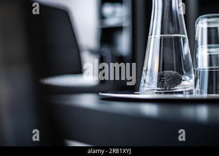 A white table is seen with a clear mug of water and two small glasses placed on its surface Stock Photo