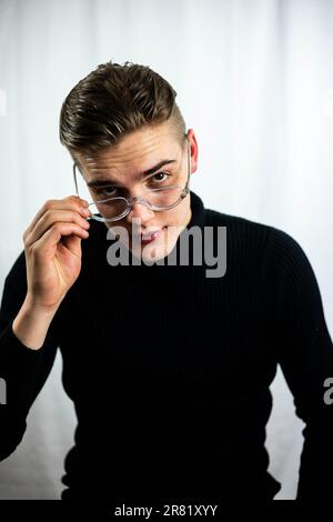 A mature man wearing a black shirt, glasses, and looking upwards with an expression of contemplation Stock Photo