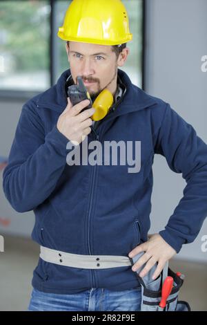 young male builder communicating by two-way radio Stock Photo